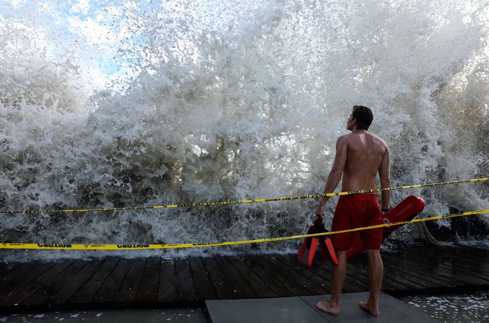 A lifeguard keeps watch along a closed boardwalk as a Pacific Ocean wave crashes over a seawall protecting homes on September 7, 2026 in Long Beach (Getty Images)