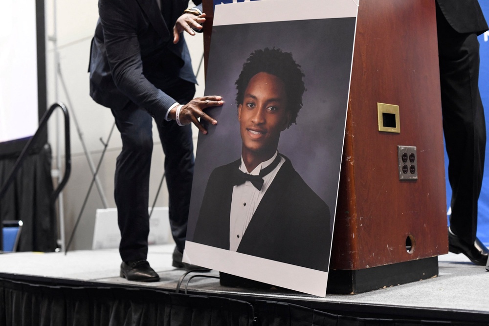 A man places a photograph of Nolan Xavier Wells in front of the podium before a news conference during the 117th NAACP National Convention at McCormick Place in Chicago, Illinois (AFP via Getty Images)