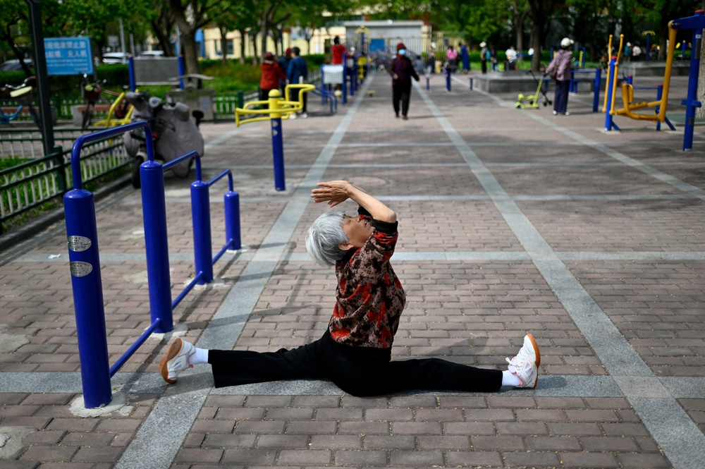 An elderly woman exercise at a public garden along a road in Beijing (AFP via Getty Images)
