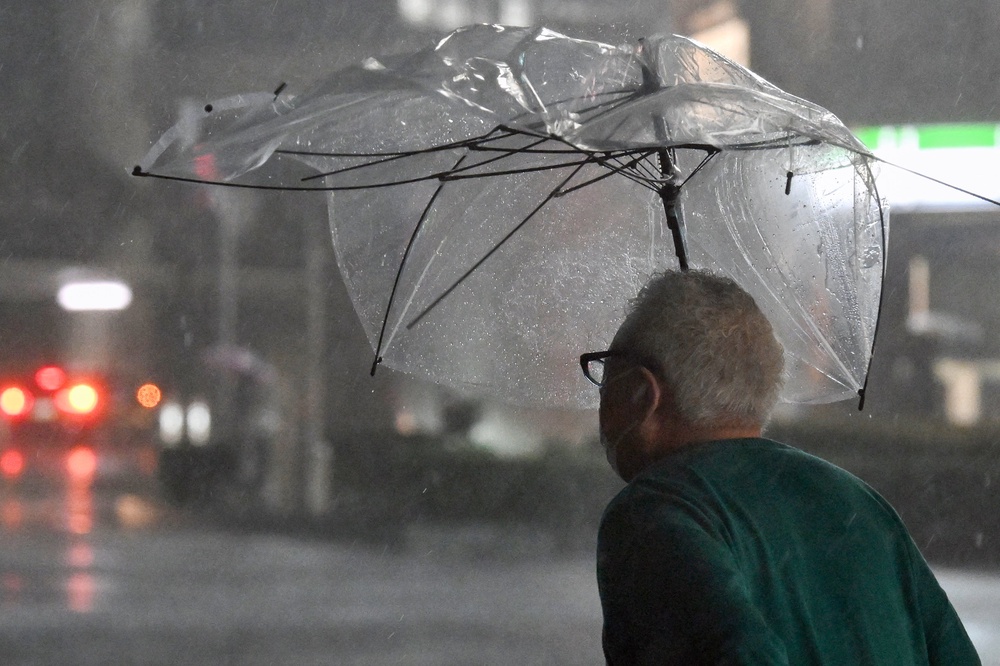 A pedestrian with a broken umbrella walks on a street amid heavy rainfall in Chiba on September 21, 2026 (AFP/Getty)