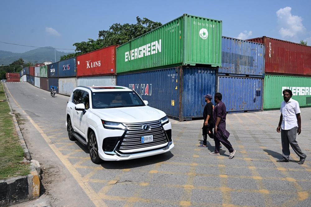 Commuters ride past shipping containers placed around Islamabad's Red Zone on 18 September 2026 ahead of opposition party Pakistan Tehreek-e-Insaf (PTI) protest demanding the release of former prime minister Imran Khan (AFP/Getty)