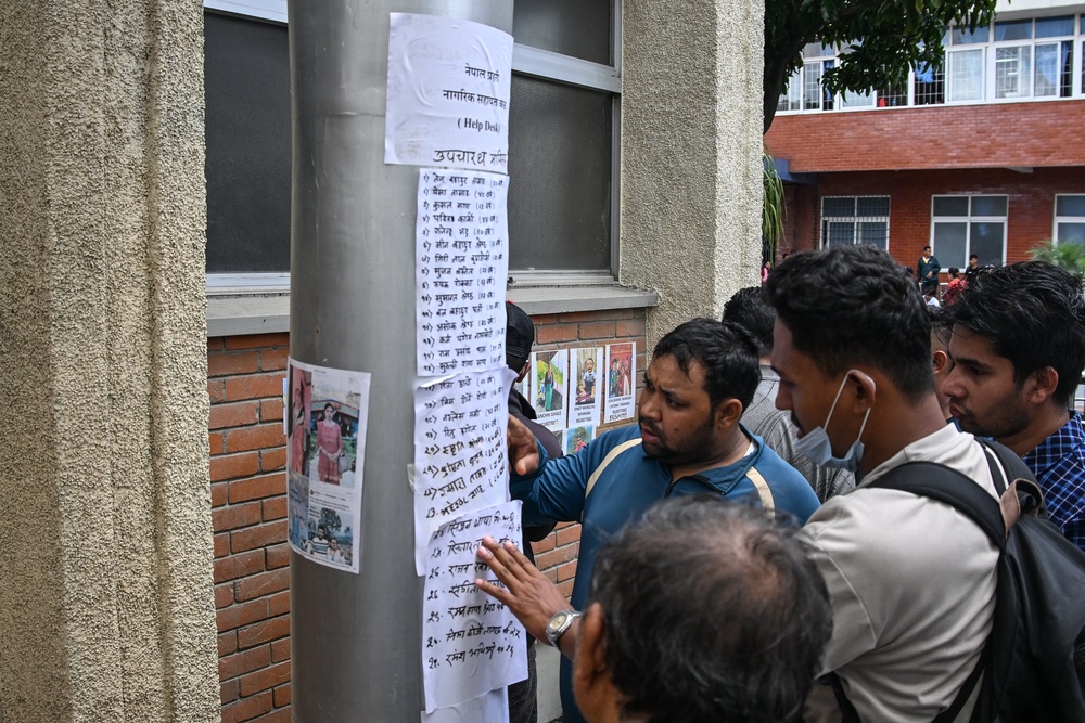 Relatives check the lists of missing people following flash floods in Nepal, outside a hospital in Kathmandu (AFP/Getty)