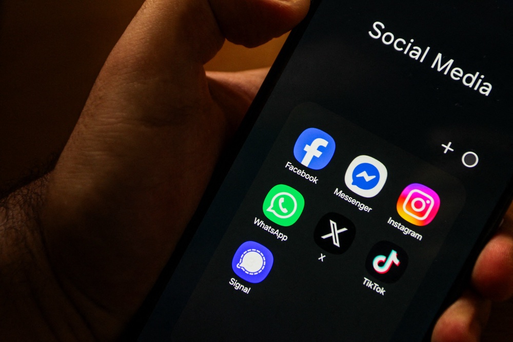A close-up image of a hand holding a smartphone displaying social media applications (Hans Lucas/AFP via Getty Images)