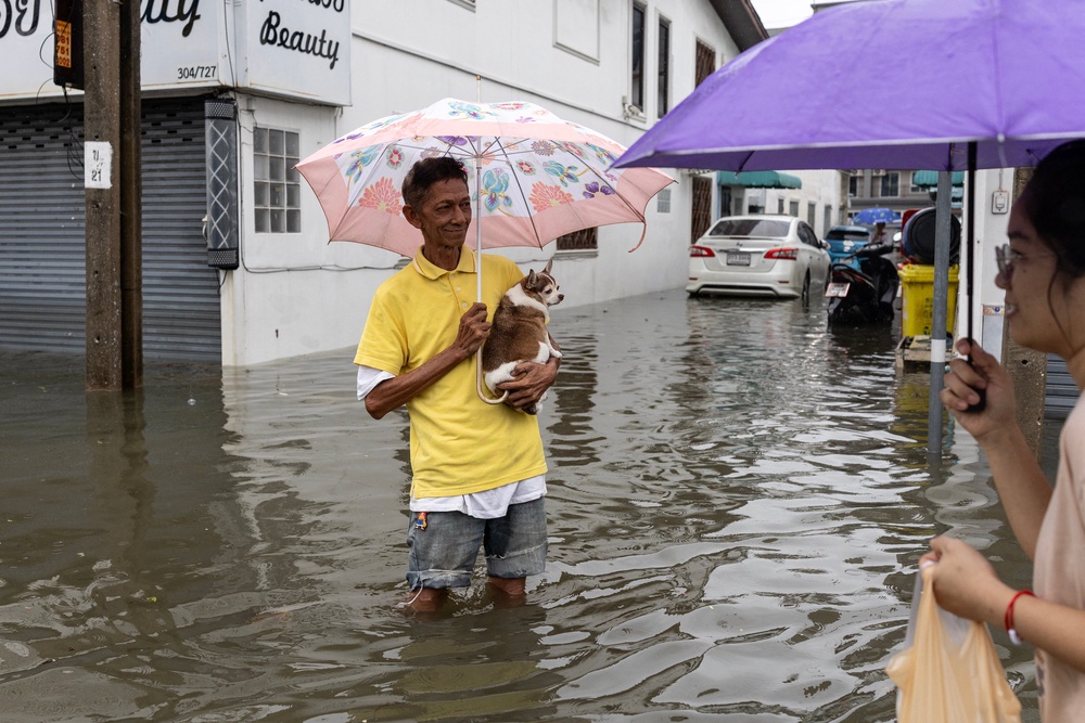 A man holding a small dog wades through floodwaters in the Bang Bua district of Bangkok on September 26, 2026 (AFP/Getty)