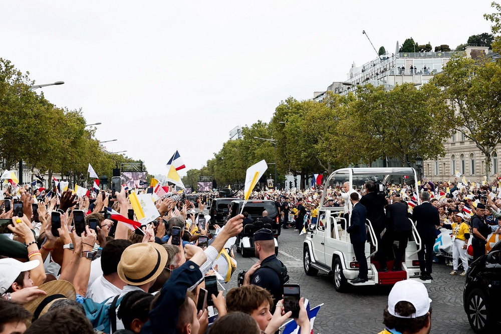 People react as Pope Leo travels in the popemobile on the Champs-Élysées avenue near the Arc de Triomphe (Reuters)