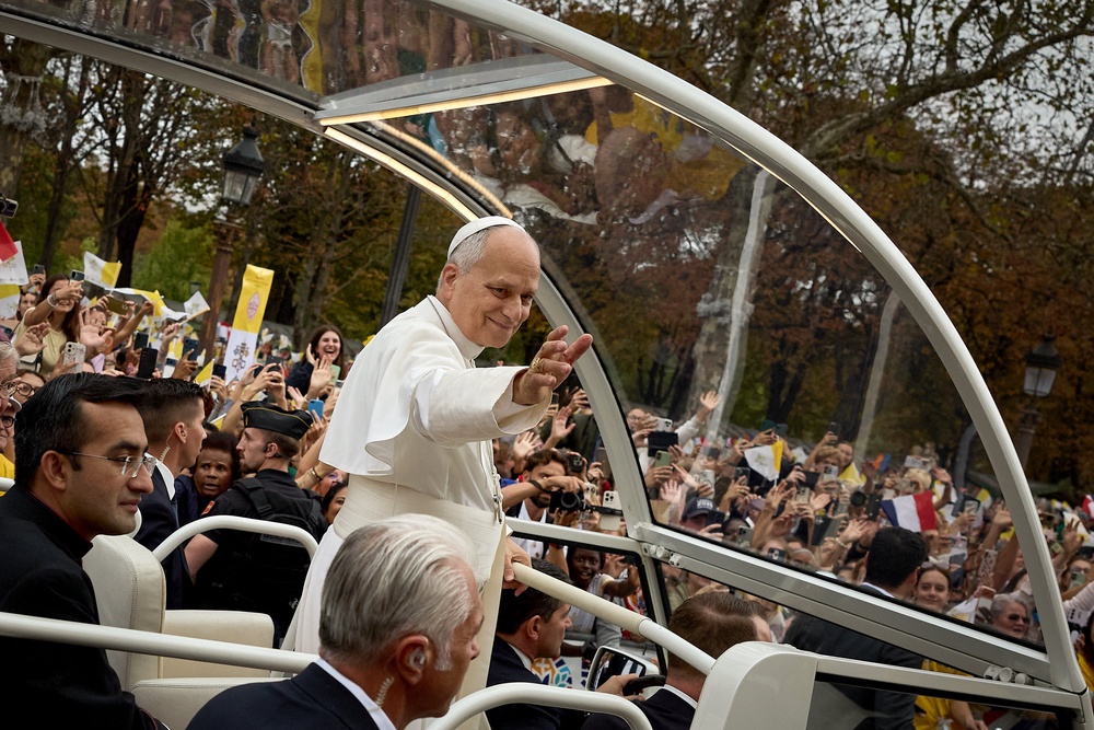 Pope Leo XIV waves to the crowd from the popemobile as he rides down the Champs-Elysees Avenue (AFP/Getty)