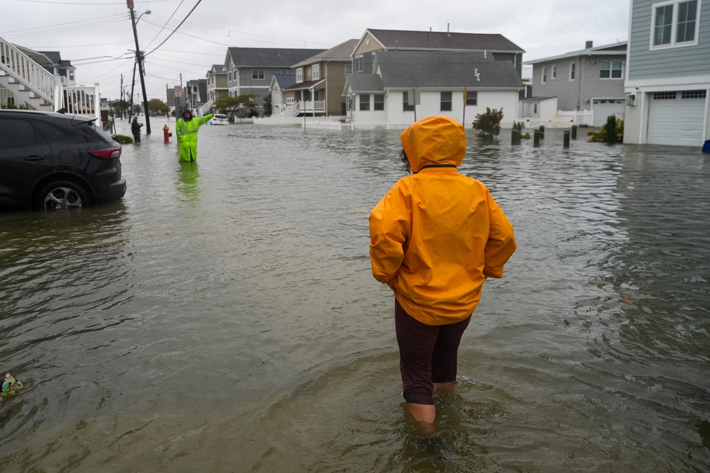 People walk through water on a flooded road during a nor'easter storm where a voluntary evacuation has been issued in Point Pleasant, New Jersey (Getty Images)