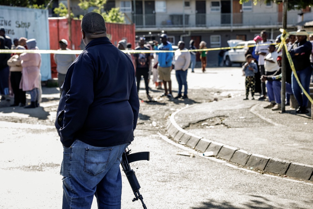 A member of the South African Police Service (SAPS) stands guard as bystanders look on behind police tape near an entertainment venue in Somerset West on September 27, 2026, after gunmen stormed the premises (AFP/Getty)