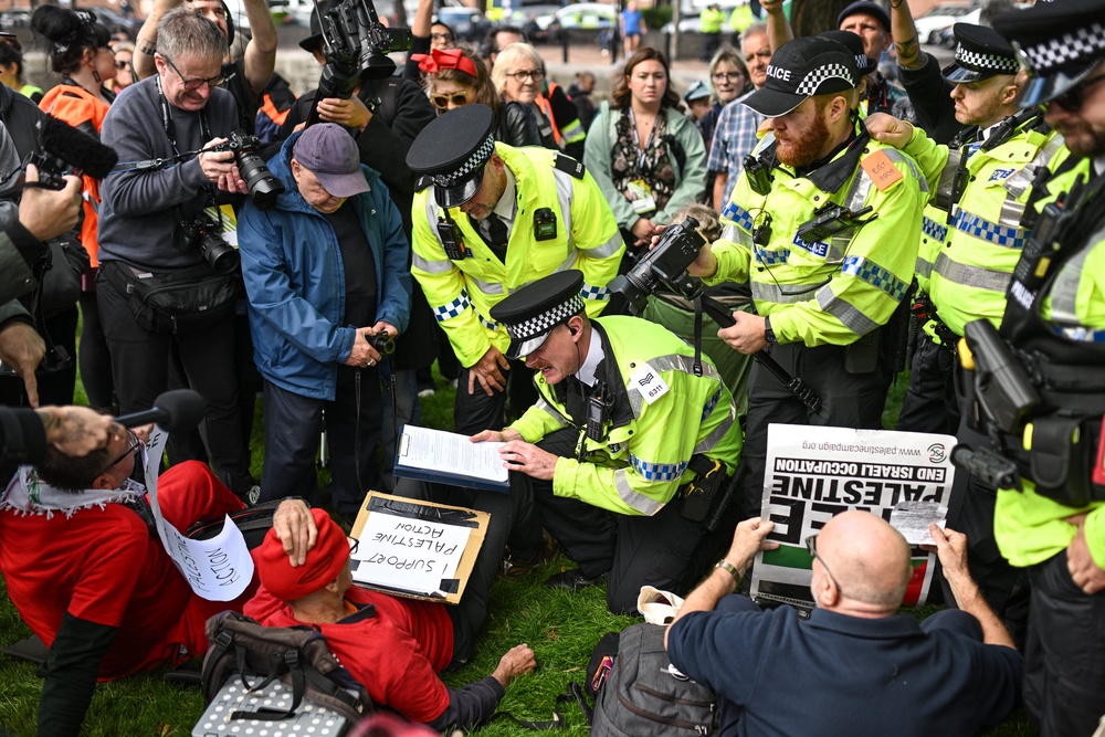 Police officers (R) begin to arrest protesters (bottom) during a demonstration in support of the proscribed group Palestine Action (AFP/Getty)