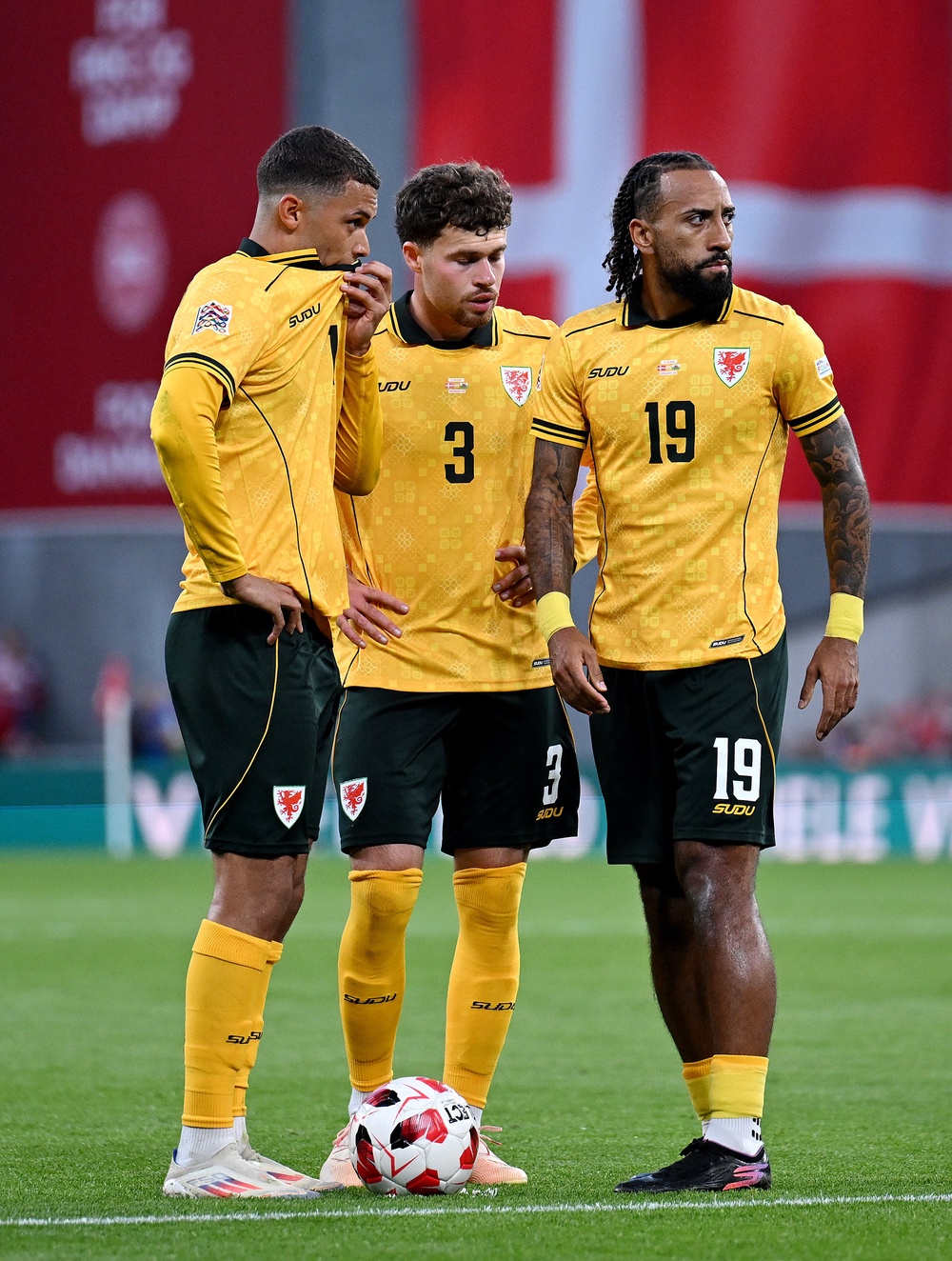 Brennan Johnson, Neco Williams and Sorba Thomas of Wales talk as they stand over the ball (Getty)