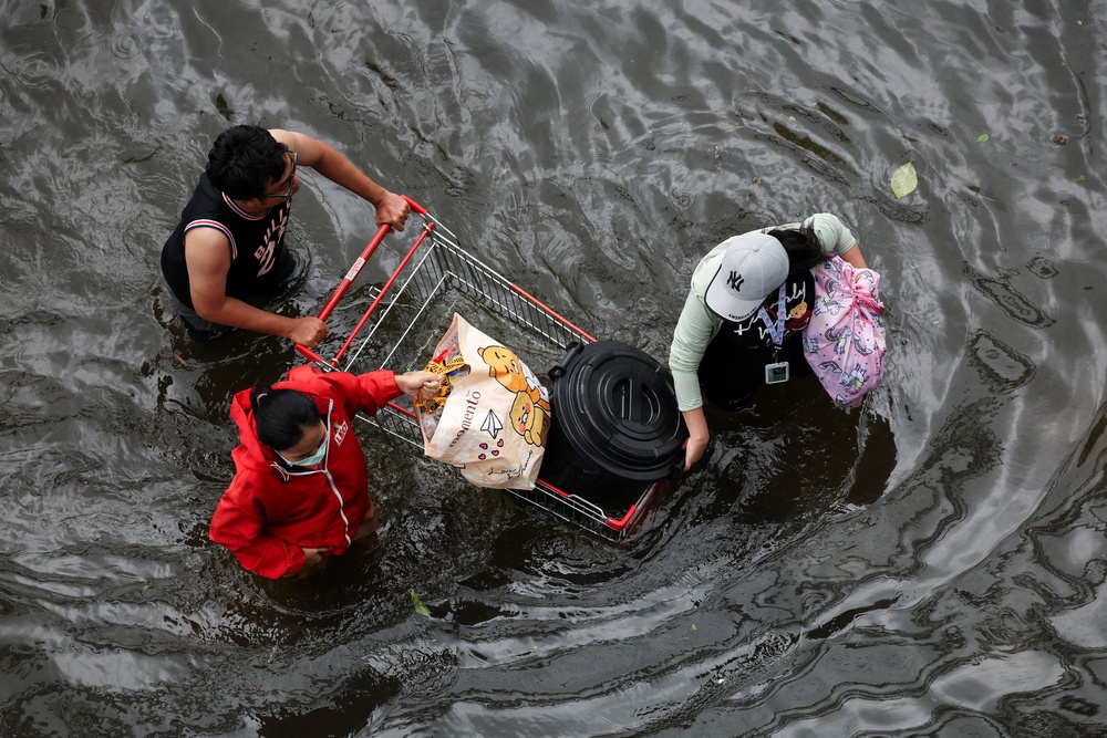 People push a shopping cart from a supermarket in Bangkok (Reuters)