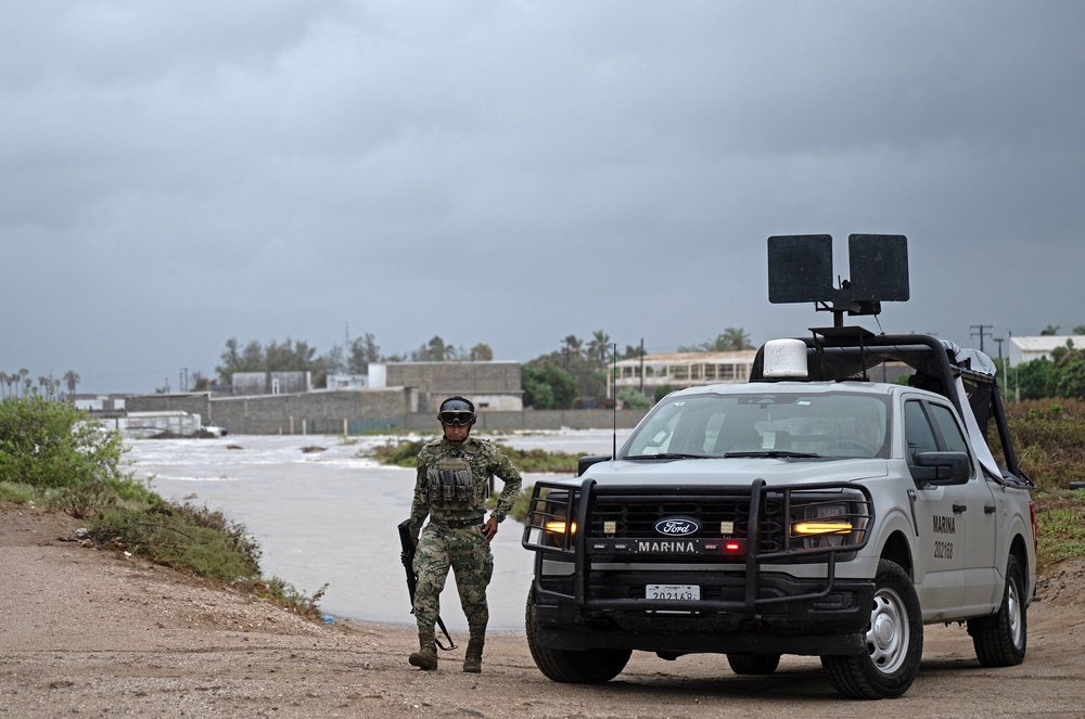 A member of Mexico's Navy walks away from a levy which broke due to a surge in water levels in Puerto San Carlos, Baja California Sur (AFP/Getty)