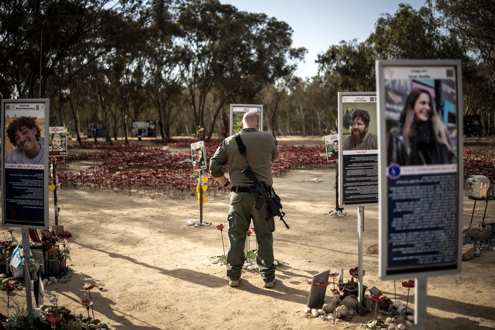 An Israeli army soldier pays his respects to the memorial of a victim of the October 7 attacks in Reim (AFP/Getty)