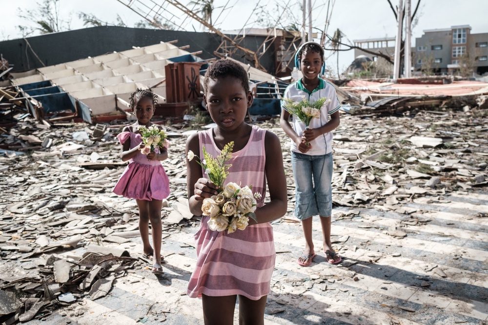 Girls collect artificial flowers from the rubble of a building destroyed by a cyclone in Mozambique (AFP/Getty)