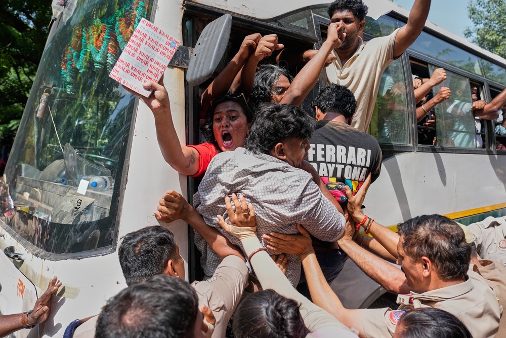 Socialist, left-wing parties and student activists shout slogans from a police vehicle after being detained during a protest in Delhi on Friday (AP)