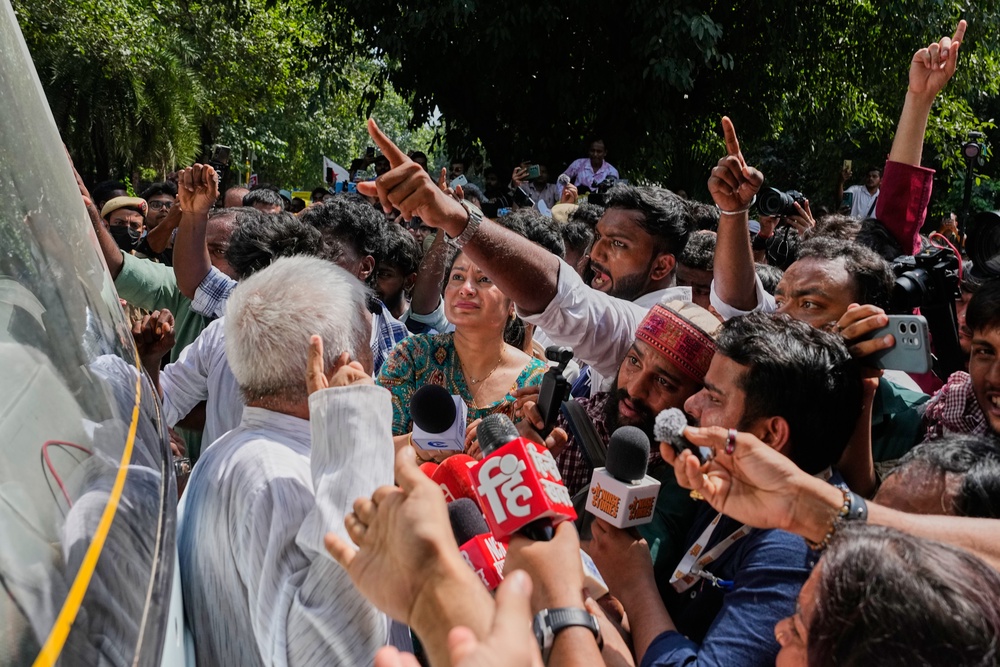 Demonstrators try to stop a police bus carrying detained fellow protesters in Delhi, on 2 October 2026 (AP)