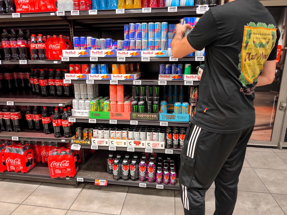 A man stands in front of the shelves of a section of iron cans of energy drinks sweetened with taurine from the brands Redbull, Monster and Celsius and grabs a package in an InterMarche supermarket in Valence, France, on September 7, 2025 (AFP/Getty)