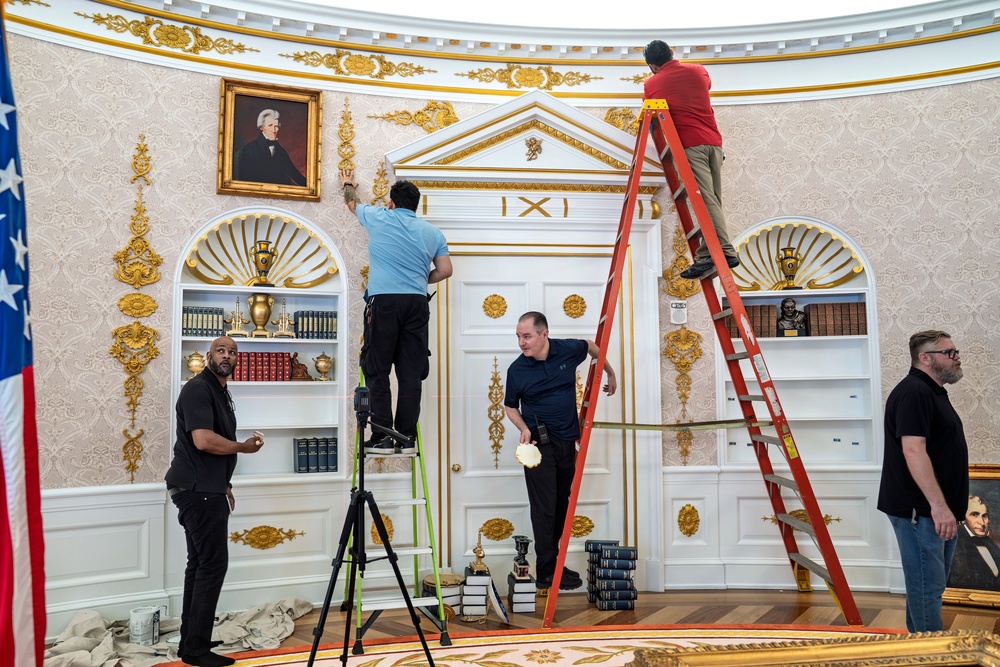 A replica of President Donald Trump's Oval Office is updated to the current decor by workers at 