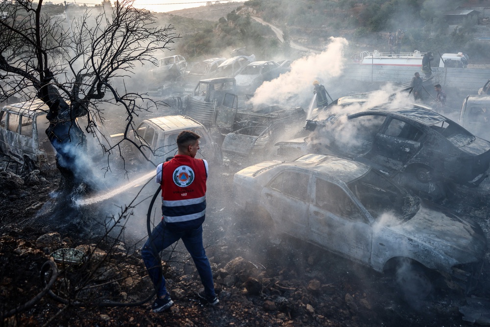 A Palestinian man helps put out a fire that burnt through cars and olive trees at a scrapyard following an attack allegedly carried out by Israeli settlers in the village of Ayn Yabrud, northeast of Ramallah, in the Israeli-occupied West Bank, on October 4, 2026 (AFP/Getty)