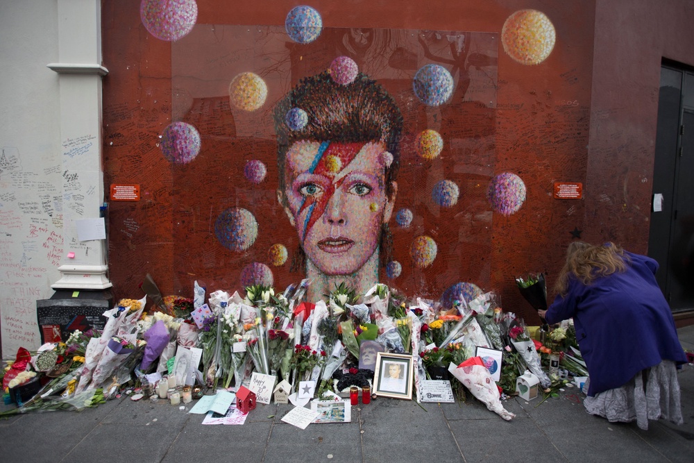A woman lays flowers at the mural of late British pop icon David Bowie created by Australian street artist James Cochran (AFP/Getty)