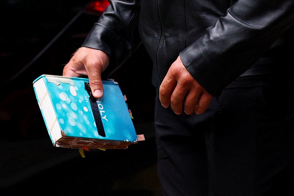 Russell Brand’s bodyguard holds a Bible as they make their way into court (Reuters)