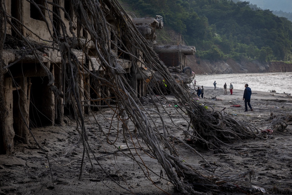 People stand in front of the damaged houses following the deadly flash floods and mudslide, at Devighat, Nuwakot district, Nepal, September 8, 2026 (Reuters)