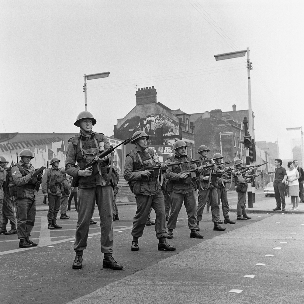 A line of British troops stands guard in the Falls Road area of riot-torn Belfast (PA)