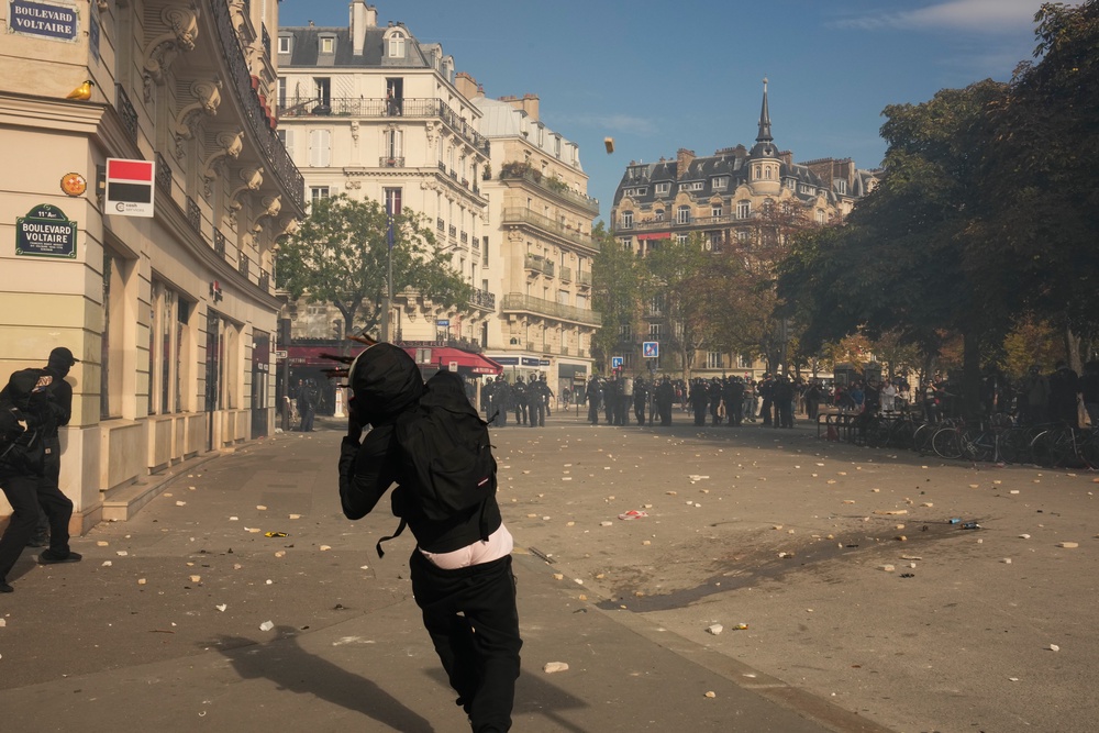 A person throws a stone at waiting riot police in Paris (AP)