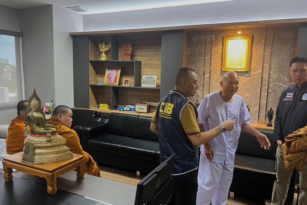 Alongkot Poonmook, formerly known as Phra Ratcha Wisutthiprachanat, second right in white, talks to police personnel at the Central Investigation Bureau in Bangkok (Central Investigation Bureau)