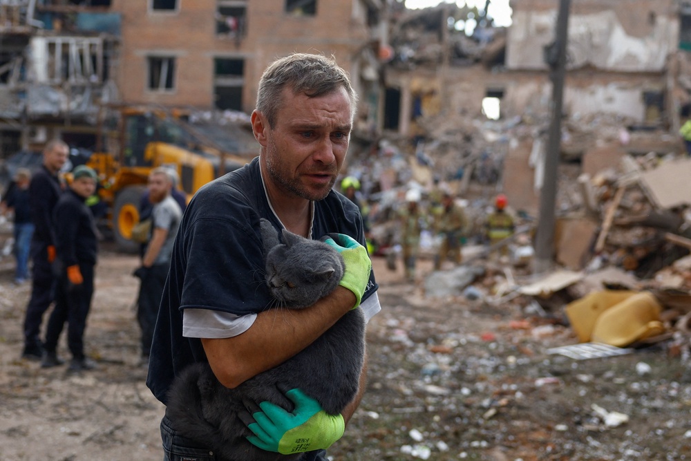 A volunteer carries a cat found at the site of an apartment building hit by a Russian missile strike in the town of Pryluky (Reuters)