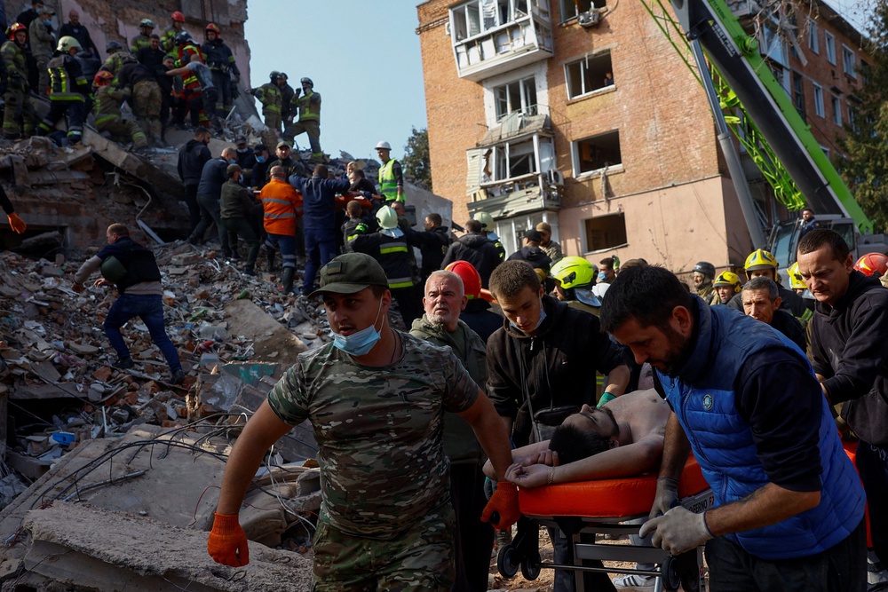 Emergency employees and volunteers carry a resident found under debris in the town of Pryluky (Reuters)