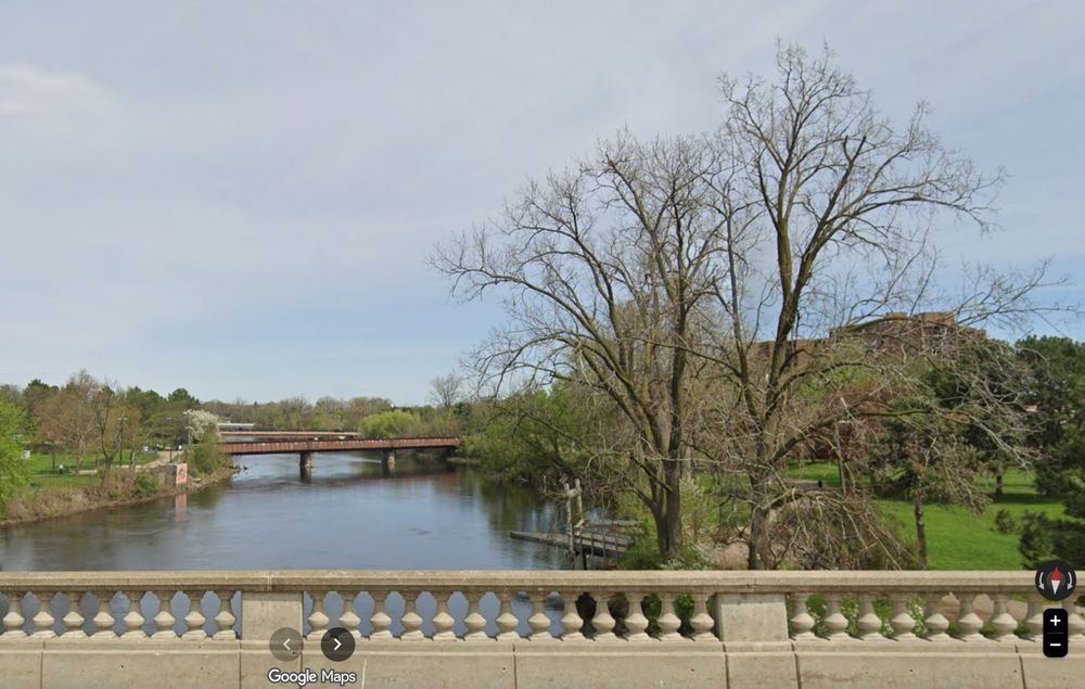 A view of the Grand River and a portion of the Lansing River Trail in Lansing, Michigan — city officials have deployed mobile surveillance trailers and extra night patrols along the greenway as unhoused residents report fearing an outside attacker (Google Maps)