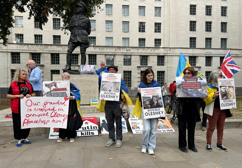 Larysa, 72, Oleshky resident who fled the town shortly after Russia's full-scale invasion of Ukraine in February 2022, holds posters as she participates in a rally demanding the establishment of a humanitarian corridor to evacuate Ukrainian civilians from her hometown (Reuters)