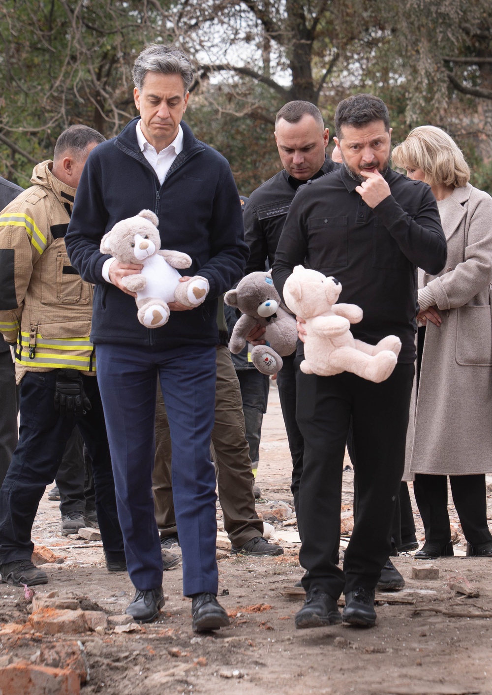 Miliband (left) and Zelensky left bears at the site of the attack, which killed five children (PA)