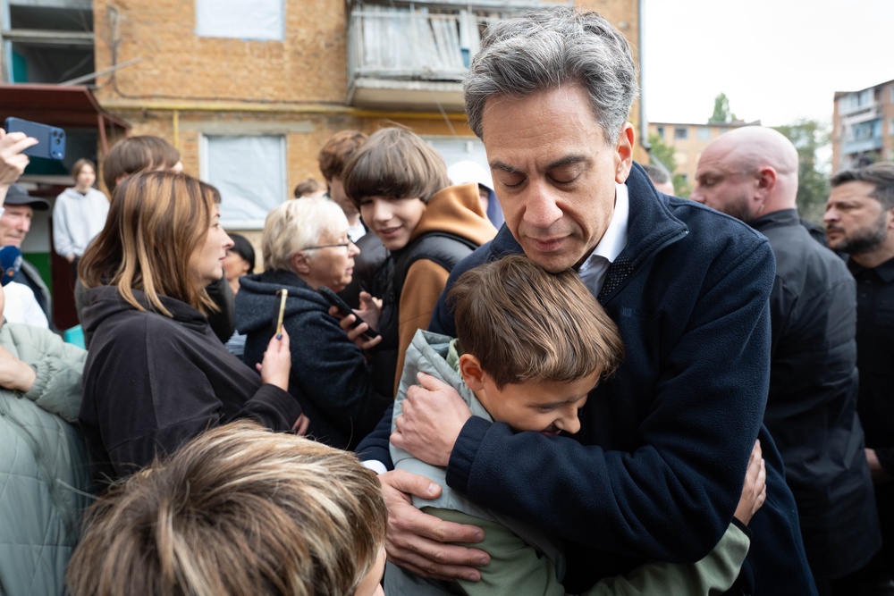 Foreign secretary Ed Miliband embraces a local resident during a visit to the site of a Russian missile strike, which hit a residential area in Pryluky (PA)
