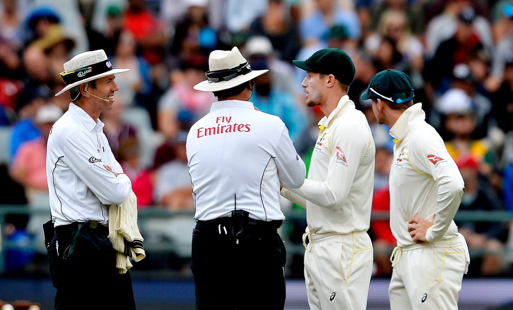 Bancroft is confronted by the umpires as Smith listens in (Getty)