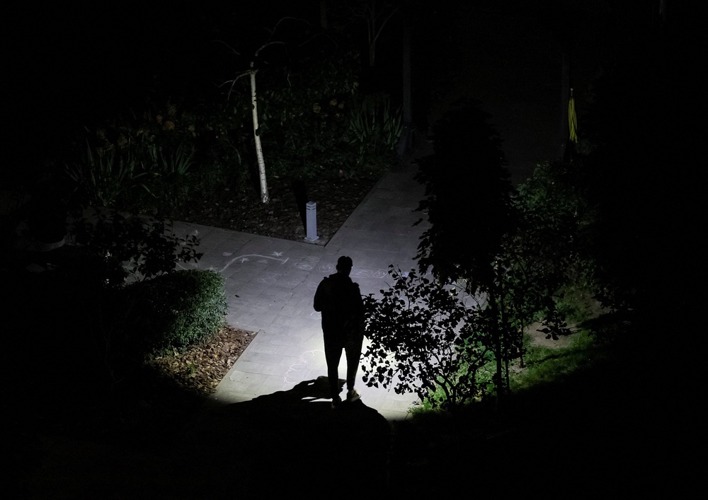 A resident uses a flashlight as he walks his dog during a power blackout after critical civil infrastructure was hit by Russian missile and drone attacks, amid Russia's attack on Ukraine, in Kyiv (Reuters)