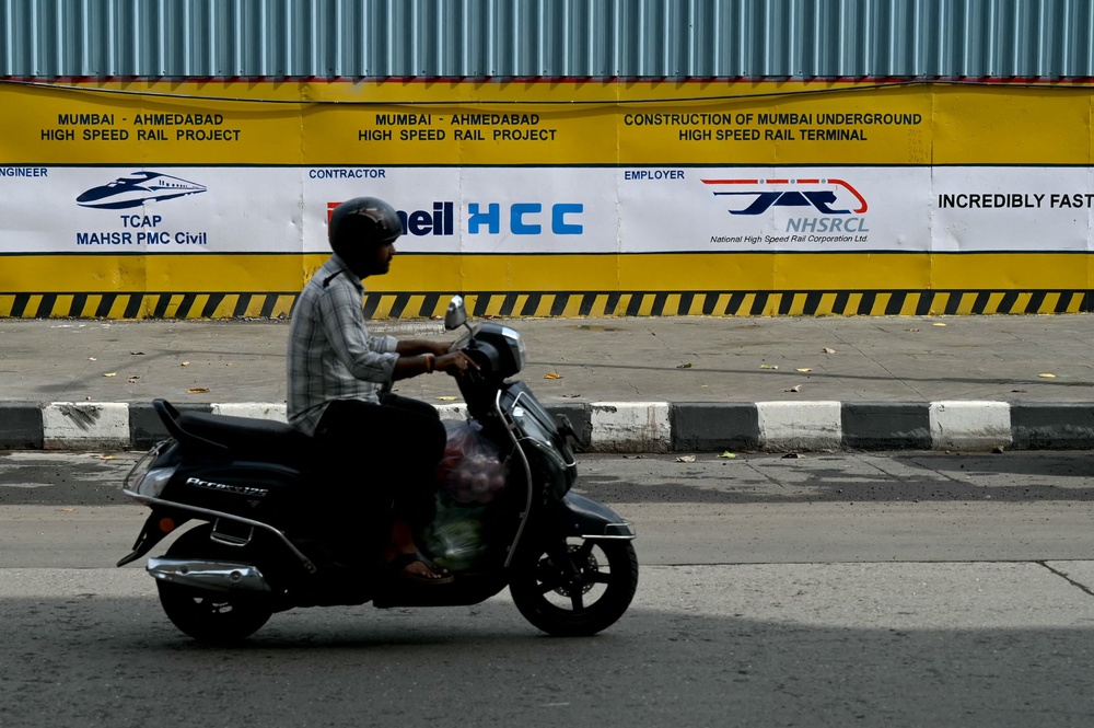 File. A commuter rides past signages at the construction site of the Ahmedabad-Mumbai high-speed bullet rail project in Mumbai on 25 June 2026 (AFP/Getty)