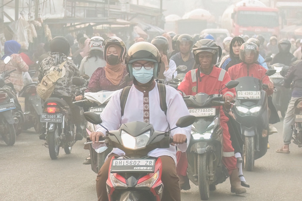People commute along a road as haze from forest and land fires shrouds Palembang, South Sumatra, on 2 October 2026 (AFP/Getty)