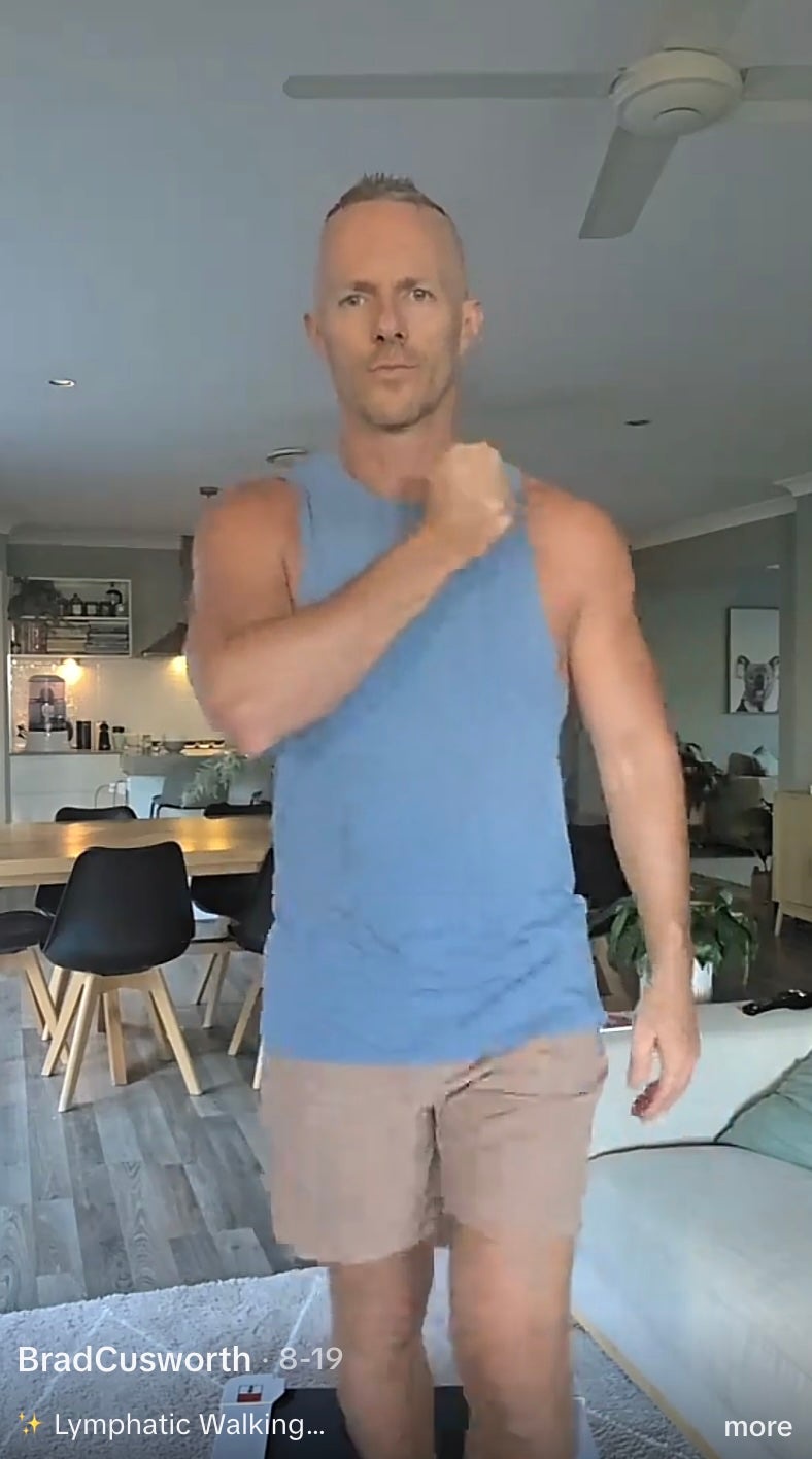 One TikTok user taps his chest while lymphatic walking on a walking pad. Swinging the arms is supposed to help fluid move through tissue that filters out harmful cells and other substances (@bradcusworth/TikTok)