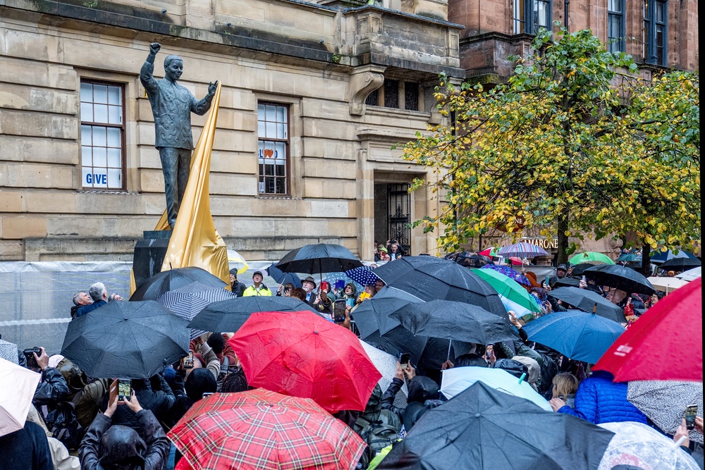 The crowd sheltered under umbrellas as the cloth was pulled off the statue (Jane Barlow/PA) (PA Wire)