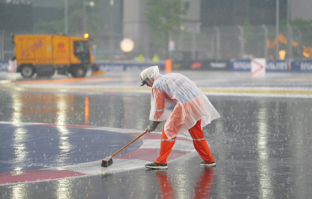 Track marshals sweep standing water from the surface (David Davies/PA) (PA Wire)