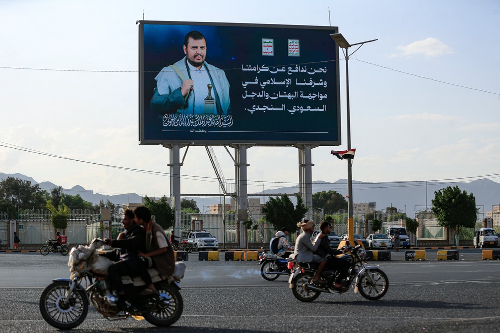 Yemeni men ride their motorcycle past a digital billboard featuring the image of Houthi leader Abdul-Malik al-Houthi in Sanaa on October 11, 2026 (AFP/Getty)