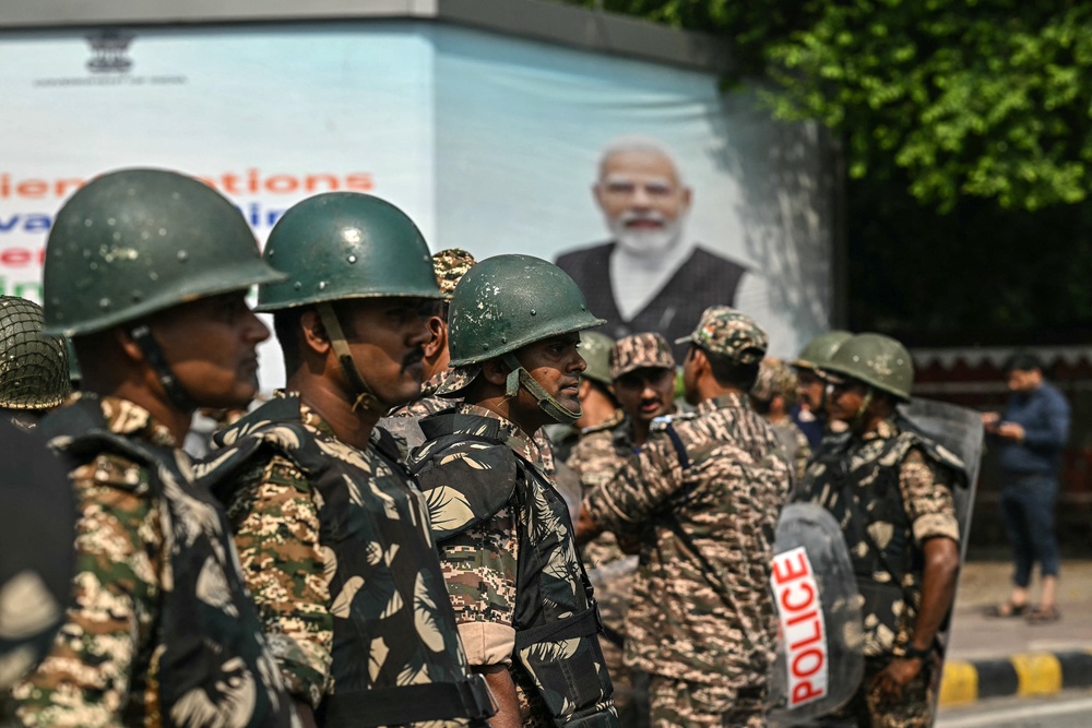 Security personnel stand guard on a road behind a portrait of India's prime minister Narendra Modi during a protest by Congress party supporters demanding the resignation of India's Chief Election Commissioner Gyanesh Kumar over alleged voter roll irregularities linked to the special intensive revision, in New Delhi on 12  October 2026 (AFP/Getty)