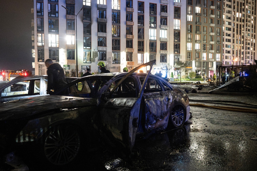 Ukrainian firefighters inspect burned vehicles in front of a high-rise residential building damaged following a Russian drone attack, in Kyiv (AFP/Getty)