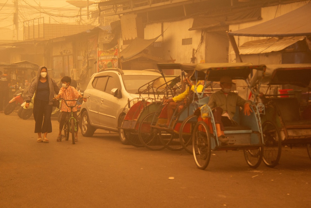 People wearing protective masks walk through the street as haze from wildfires shrouds the area in Palangka Raya, Central Kalimantan province, Indonesia, October 14, 2026 (Reuters)
