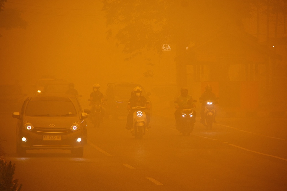 Motorists drive through a main road as haze from wildfires shrouds the area in Palangka Raya, Central Kalimantan province, Indonesia, October 14, 2026. (Reuters)