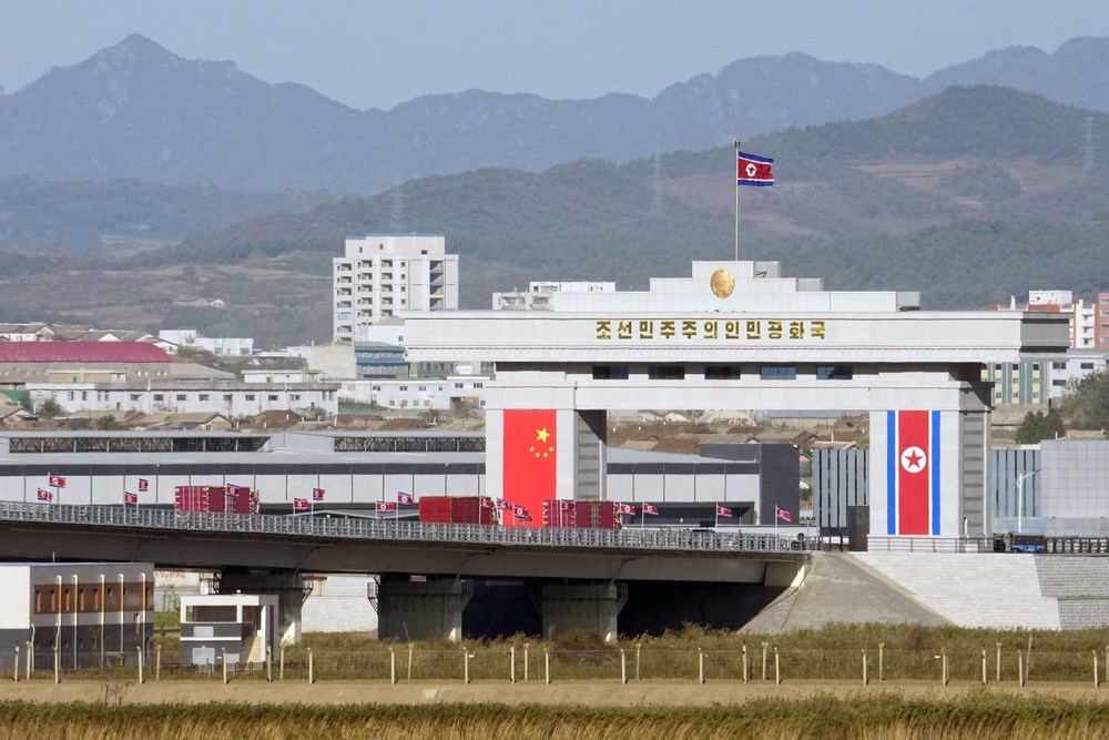 National flags of China and North Korea are seen around a gate leading to a North Korean customs facility, seen from Dandong, China, ahead of the opening ceremony of the China-North Korea Yalu River Bridge at the border between the two countries (Iori Sagisawa/Kyodo News via AP)