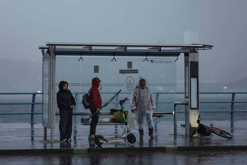 People shelter from heavy rainfall at a bus stop in Uskudar district, Istanbul, on October 14, 2026 (AFP/Getty)