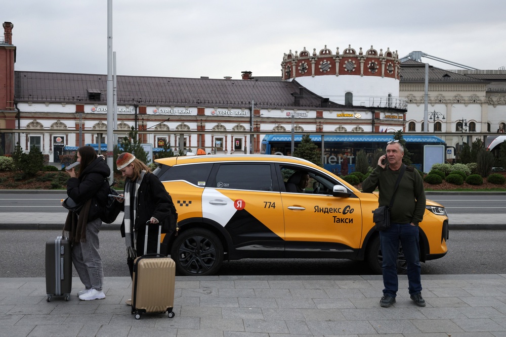 People stand next to a Yandex Taxi car on a street in Moscow, Russia, October 11 (Reuters)